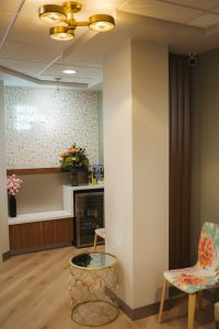 A textured white wall adorned with text, including phrases like 'smile,' 'breathe,' and 'live,' is complemented by a vase of flowers | cosmetic dentist lakewood co