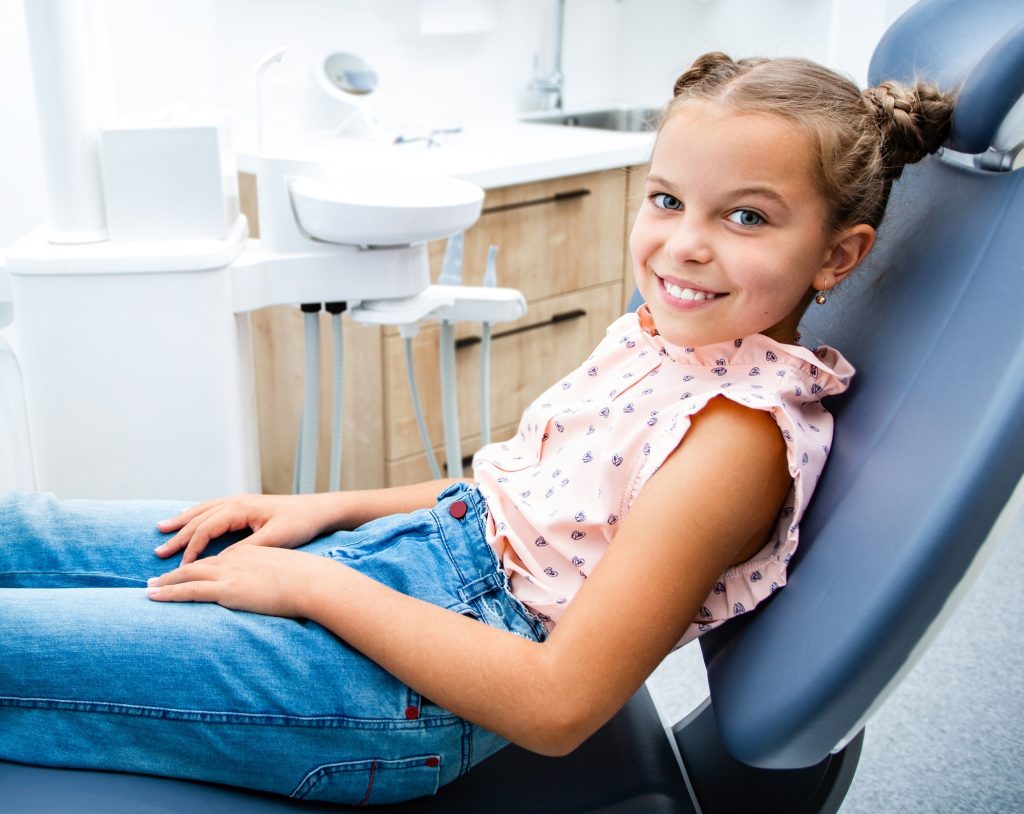 Child smiling while sitting in the dentist's chair. Kid teeth treatment