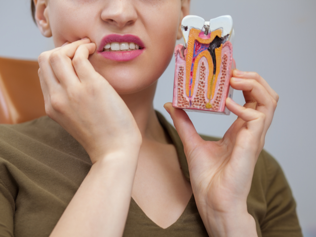 woman holding her face and a tooth model